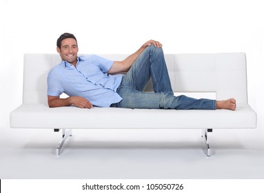 Barefoot man lying on a couch