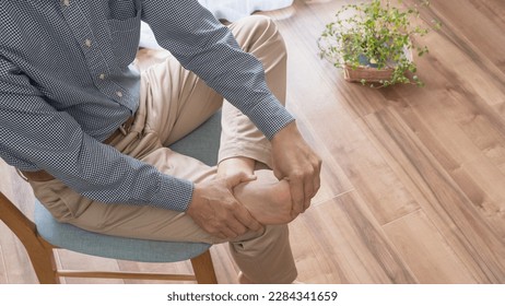 A barefoot man sitting on a chair.A man giving a foot massage.People with gout.