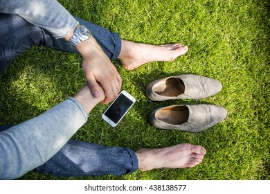 Barefoot Man Sitting On Grass