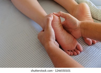 The barefoot massages for a girl in bed with a blue blanket in the morning make for a relaxing and fulfilling life for the couple.