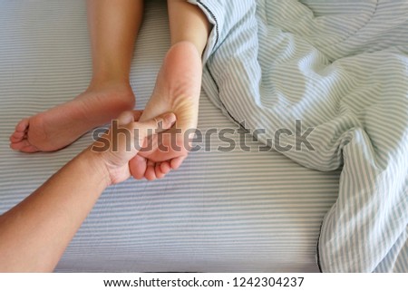 The barefoot massages for a girl in bed with a blue blanket in the morning make for a relaxing and fulfilling life for the couple.