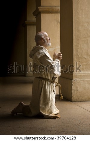 Barefoot monk praying on his knees in a monastery