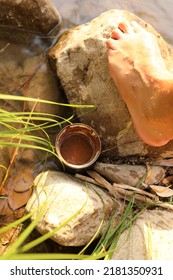 Barefoot Next To Riverside Water, Rocks And Raw Cacao Cup