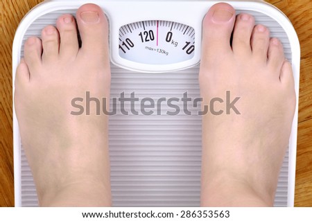 Barefoot overweight person standing on the scale