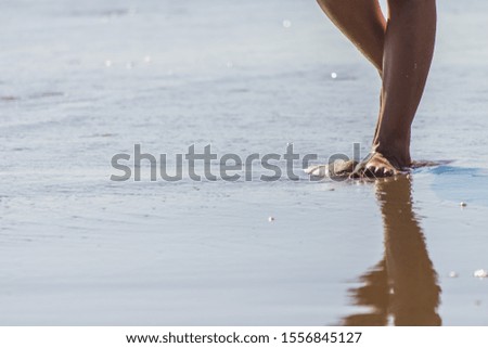 Barefoot reflected on the water of the beach 