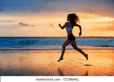 Barefoot Sporty Girl Silhouette Running Along Ocean Surf By Water Pool To Keep Fit And Health. Sunset Black Beach Background With Sun. Woman Fitness, Jogging Sport Activity On Summer Family Holiday.