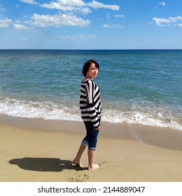 Barefoot Teen Girl In Jeans On An Empty Sea Beach.