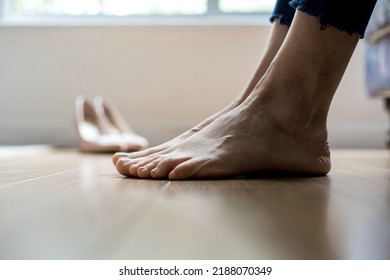 Barefoot Woman, Focus On Feet And Shoes In Blur. Symbolic Image Resting The Feet After Walking With High Heel Shoes Backlit Image.