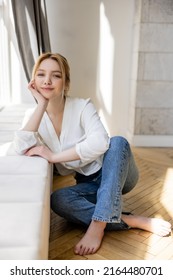 Barefoot Woman In Jeans Smiling At Camera Near Windowsill At Home