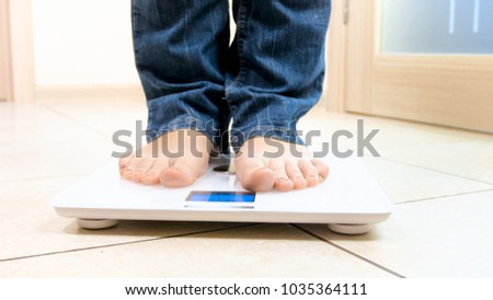 Barefoot woman in jeans standing on digital scales