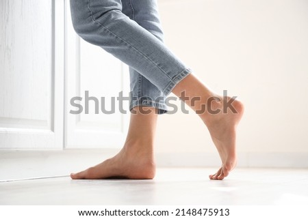 Barefoot woman near counter in kitchen, closeup