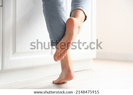 Barefoot woman near counter in kitchen, closeup