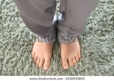 Barefoot woman on green carpet at home, closeup