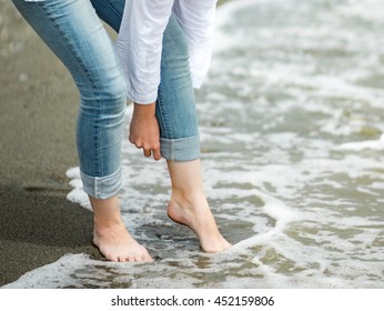 Barefoot woman rolling her pants on the beach - Powered by Shutterstock