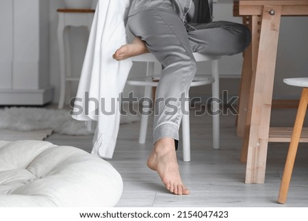 Barefoot woman sitting in chair at home