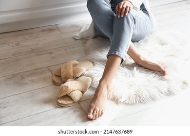 Barefoot Woman With Slippers Sitting On Floor In Kitchen