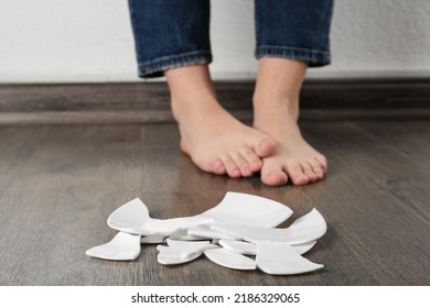 Barefoot Woman Standing Near Broken Plate On Floor, Closeup