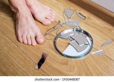 Barefoot Woman Stands Near A Broken Mirror On The Wooden Floor At Home