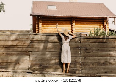 Barefoot Woman Talking Over A Wooden Fence To Her Neighbors.