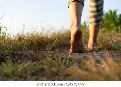 barefoot woman walking on the ground with sunset light in the countryside