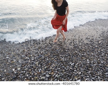 barefoot young girl walking shore line at sunset
