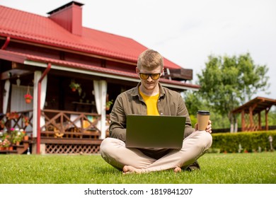 barefoot young man wearing yellow glasses sitting on green grass with laptop. Young millennial male student searching information for homework outdoors on sunny summer day. Freelance work concept - Shutterstock ID 1819841207