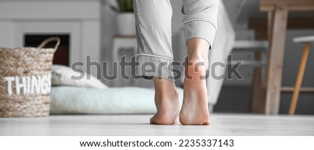 Barefoot young woman in pajamas at home