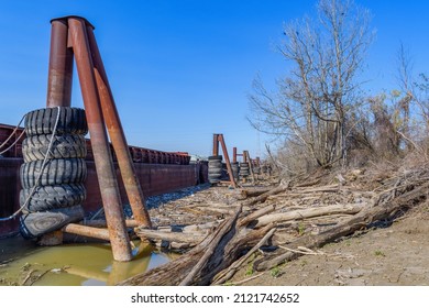 Barge docking area along the east bank of the Mississippi River with trash and organic debris along the shoreline