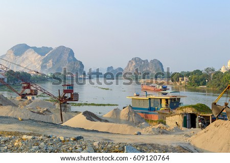 Barge loading sand by the crane. River in mountain region in Vietnam