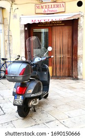 Bari, Italy-April 2019: Close Up Of Vespa Parked In Front Of Typical Italian Butcher Shop Storefront