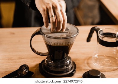 Barista is brewing clever coffee dripper in cafe. Close-up process of brewing pour over filter clever coffee dripper in cafe