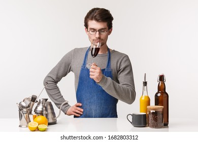 Barista, Cafe Worker And Bartender Concept. Portrait Of Elegant And Serious-looking Young Male In Apron Sommelier Tastes New Flavour Of Wine, Sniff Smell Of Drink From Glass With Closed Eyes