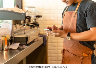 Barista checking cell phone in coffee shop. - Powered by Shutterstock