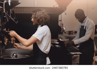 Barista control grounds roasting process of beans, test aroma. Man working at coffee production.