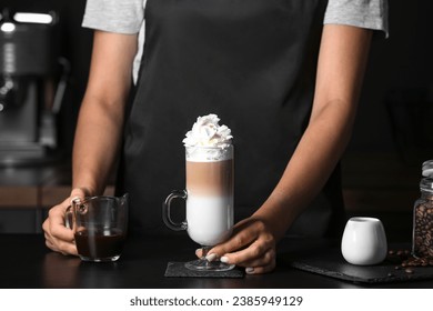 Barista holding glass of tasty latte with whipped cream in cafe - Powered by Shutterstock