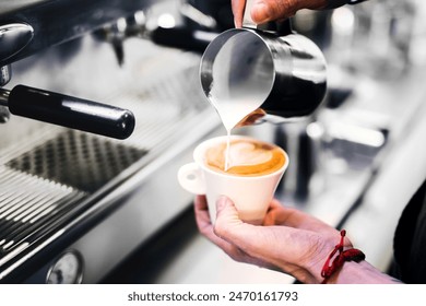 Barista holding and preparing cappuccino, latte art. Bartender in apron preparing coffee drink. - Powered by Shutterstock