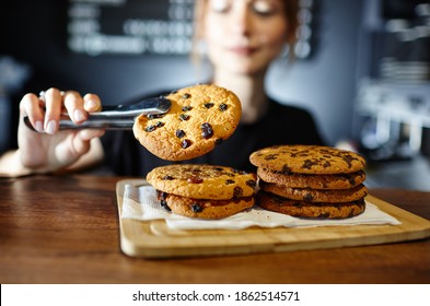 Barista holds tasty cookie at bar counter in coffee shop. Blurred image, selective focus - Powered by Shutterstock