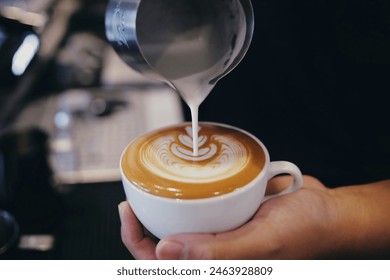 Barista pouring milk  into a coffee mug,Close up barista hand pouring milk for making latte art in cafe. - Powered by Shutterstock