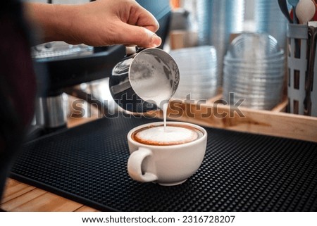 barista pouring milk into coffee making cappuccino. Professional barista preparing coffee on the counter.
