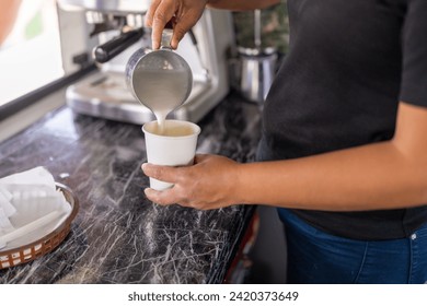 Barista pouring milk into a cup of cappuccino working in a food truck - Powered by Shutterstock