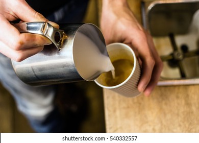 Barista Pouring Milk To Takeaway Coffee. Close-up View On Hands, Barista Coffee Preparation Service Concept.