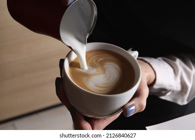 Barista pouring steamed milk from pitcher into cup of aromatic coffee in cafe, closeup - Powered by Shutterstock