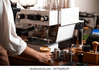 A barista prepares a latte at a professional espresso machine in a cozy coffee shop. The scene captures the meticulous process of brewing coffee, with various barista tools. - Powered by Shutterstock