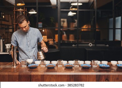 Barista preparing coffee tasting with rows of cups and beans - Powered by Shutterstock