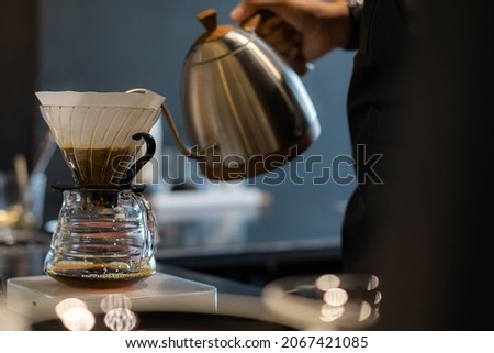 Barista preparing coffee using pour over coffee maker and drip kettle. Alternative ways of brewing coffee. Coffee shop concept.