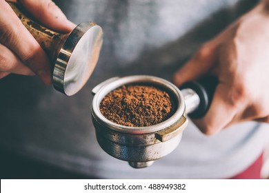 Barista presses ground coffee using tamper. Toned picture - Powered by Shutterstock