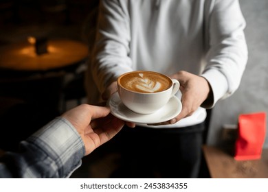 Barista Serving a Freshly Made Cappuccino With Artful Foam giving it to the client's hands - Powered by Shutterstock