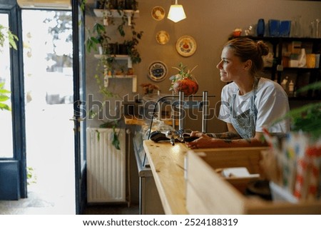 A barista smiles while serving in a charming caf adorned with plants and decor
