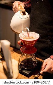 The Barista Spills Hot Water And Makes Coffee Using The Funnel Method. The Barista Works Behind The Counter.