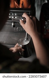 barista steaming milk at an espresso machine in a cafe